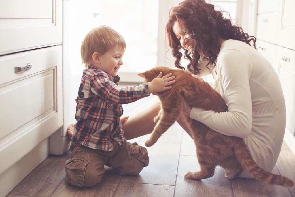 Mother with her baby playing with pet on the floor