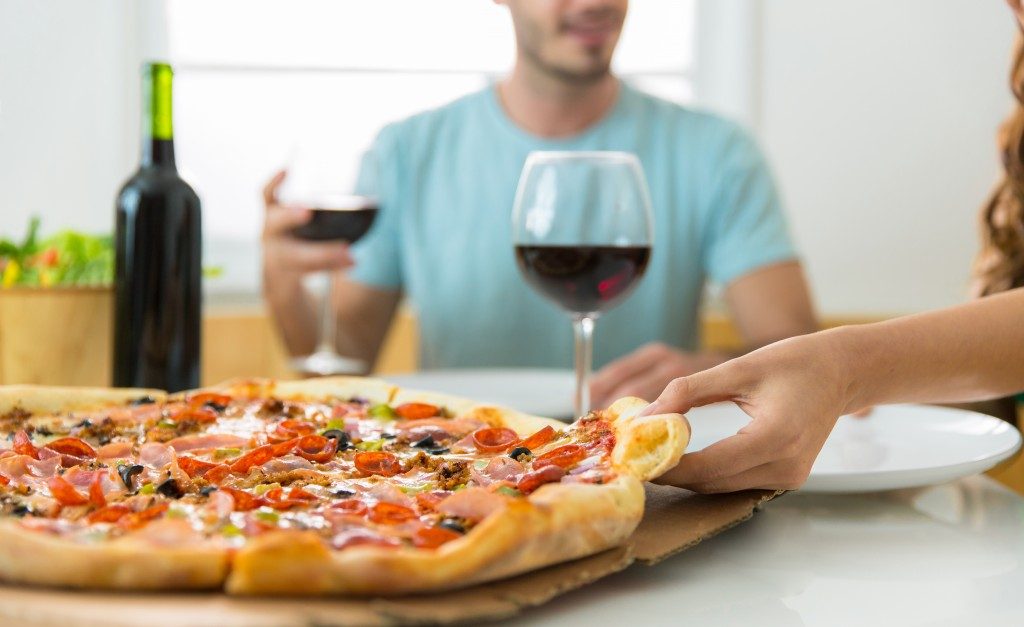 couple eating pizza and having wine at home