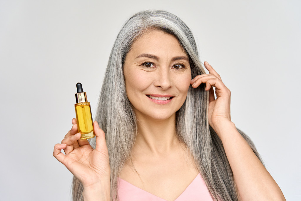 aging woman holding a bottle of serum
