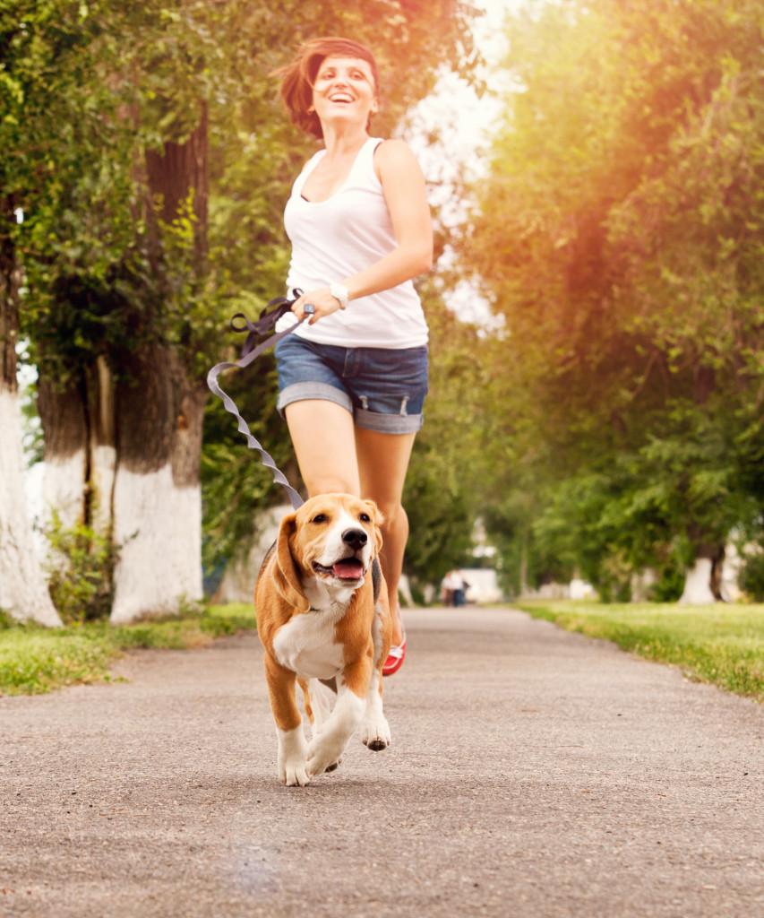 A woman following a running dog on a leash